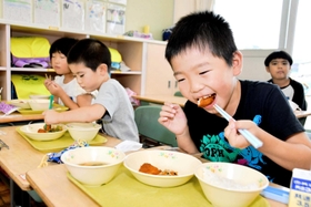 おいしそうに鶏肉をほおばる児童＝多可町中区森本