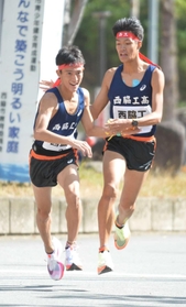 男子・西脇工の２区山中達貴選手（右）が区間新記録を達成し、３区塩田大空選手につなぐ＝西脇市総合市民センター（撮影・笠原次郎）