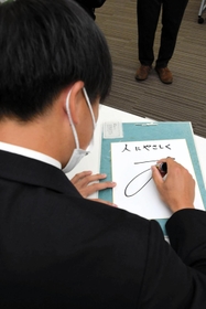 多可町の子どもたちへメッセージをしたためる翁田大勢投手＝多可町役場