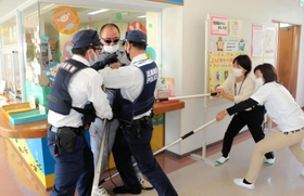 訓練で不審者役を抑え込む小野市立児童館チャイコムの職員と小野署員＝小野市浄谷町
