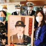 三宅文佳さん（前列右）からポスターを受け取るおかみの辻江美さん（同左）＝加西市殿原町