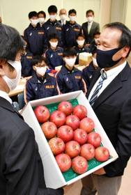 激励のため贈られたリンゴを受け取る足立監督（右）ら＝西脇市野村町