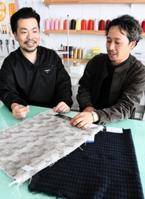 コートに使われた生地のサンプルを手にする上田さん（左）と丸山さん＝西脇市西脇