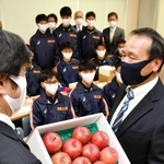 激励のため贈られたリンゴを受け取る足立監督（右）ら＝西脇市野村町