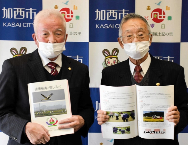 加西市老人クラブ連合会が作成した冊子を持つ山下光昭会長（左）と吉田廣顧問＝同市役所