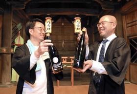 日本酒「朔」の瓶を手に、住吉神社で豊作を願う庄司英生さん（左）と稲岡敬之さん＝加西市北条町北条
