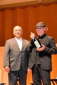 岩根正市長から委嘱状代わりの一升びんを受け取る吉田さん＝加東市上三草
