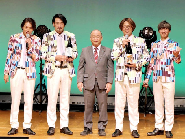 岩根市長（中央）から任命書が貼られた日本酒を受け取った純烈メンバー＝加東市下滝野（加東市提供）