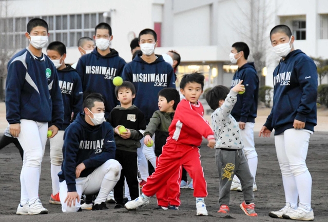 高校球児に見守られながらテニスボールを投げる子ども＝西脇市野村町