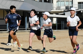 小学生と一緒にグラウンドを駆ける陸上部員＝西脇市西脇