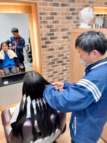 ３年以上伸ばした島村大輝さんの髪の毛にはさみを入れる父・一弘さん（島村有香さん提供）