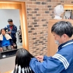 ３年以上伸ばした島村大輝さんの髪の毛にはさみを入れる父・一弘さん（島村有香さん提供）