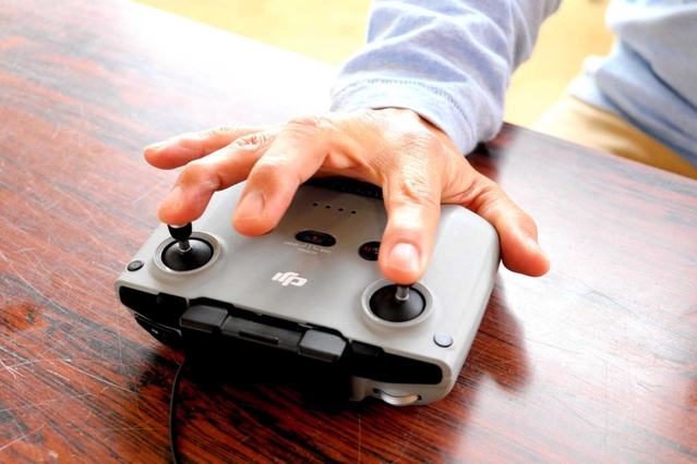 両手で操作するコントローラーを、片手で器用に使う＝三木市内