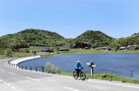 小野アルプスを背景に、見晴らしの良い鴨池近くの道を快走する＝小野市来住町