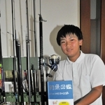 愛用の釣りざおが並ぶそばで「釣魚図鑑」を持つ小西悠貴君＝小野市黒川町