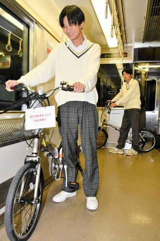 実証実験で、電車内に自転車を持ち込む男子高校生＝西脇市内
