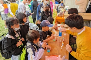 西脇高校のブースで、人工イクラ作りに挑戦する子どもたち＝西脇市野村町、茜が丘複合施設みらいえ