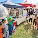 マルと記念撮影する親子連れ＝西脇市野村町、茜が丘複合施設みらいえ
