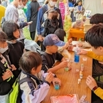 西脇高校のブースで、人工イクラ作りに挑戦する子どもたち＝西脇市野村町、茜が丘複合施設みらいえ