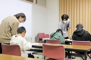 学習する子どもたちにアドバイスをして回る学生ら＝加東市社、社福祉センター
