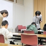 学習する子どもたちにアドバイスをして回る学生ら＝加東市社、社福祉センター