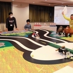 自作ロボットの動きを見守る子どもたち。チェックポイントを通ると審判の旗が上がった＝やしろ国際学習塾