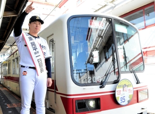 進行方向を指す東晃平投手。電車のヘッドマークには東投手がデザインされている＝神鉄小野駅