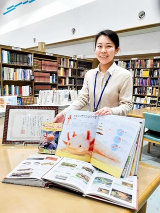 ウーパールーパーの載った図鑑や児童書を示す中村一香さん＝小野市立図書館