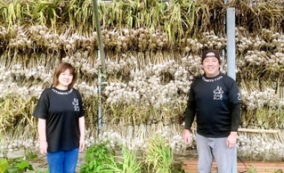 「ハリマ王の花芽は豚肉と炒めると最高です」と話す北本奇世司さん（右）と妻の千恵さん＝加西市内