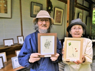 自作を手にする泉井小太郎さん（左）と、妻の音座マリカさん＝羅漢寺