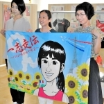 田中希実選手の応援旗を手にする（右から）田中博美さん、田中千洋さん、石井奈津子さん＝小野市役所