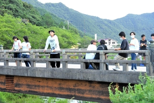 吉田田タカシさん（左から３人目）と恵まれた自然に目を向け、アイデアを膨らませる中学生＝多可町中区鍛冶屋