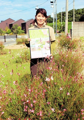 植栽した多年草に囲まれ、イベントのポスターを手にする角英津子さん＝加東市木梨