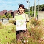 植栽した多年草に囲まれ、イベントのポスターを手にする角英津子さん＝加東市木梨