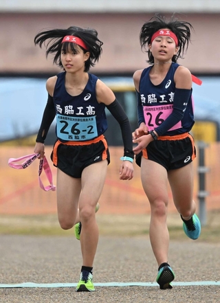 女子・西脇市の１区橋本結菜選手（右）からたすきを受ける２区橋本晴菜選手＝加古川市の加古川河川敷マラソンコース（撮影・大田将之）