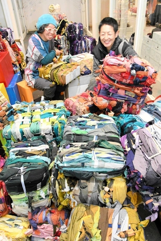 残布を巻き付け、カラフルな色合いに仕上げた「オリアイ（織り合い）」の作品とアユミアダチさん（左）、玉木新雌さん＝西脇市比延町