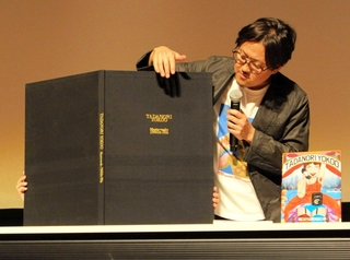 播州織が使われた作品集について説明する浅見英治さん＝オリナスホール