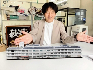 制作を手がけた黒田正憲さん。スマートフォンでＱＲコードを読み取ると、画面上に福田小学校の校舎がＡＲで現れる＝加東市社