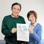 若者広場のチラシを持つ市位辰三さん、葉子さん夫妻＝てとて広場