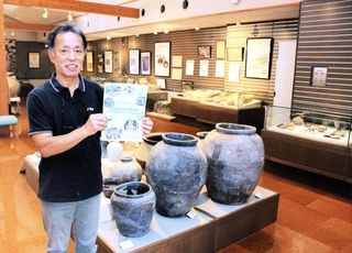 作成途中の計画の概要版を手にする安平勝利さん。館内には多可町の文化財が並ぶ＝那珂ふれあい館