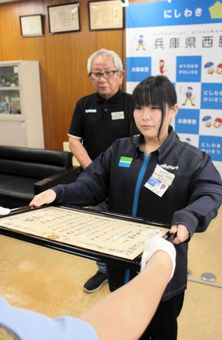 署長感謝状を受け取る細田愛玲音さん。後ろは代理の原田福信オーナー＝西脇署