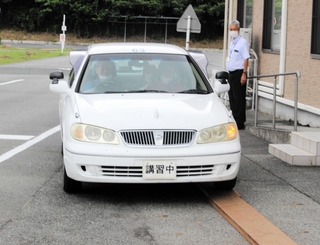 片輪を板に乗せて走行する参加者＝西脇自動車教習所