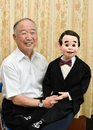 相棒の腹話術人形「シンちゃん」とともに笑顔を見せる腹話術師の春風小イチローさん＝加西市下宮木町