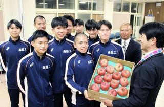 リンゴを受け取る西脇工業高校男子陸上部の選手ら＝西脇市野村町