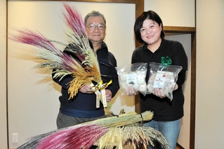 稲穂飾りや餅をＰＲする藤尾善則さん（左）と妻淳子さん＝鍬渓温泉「きすみのの郷」
