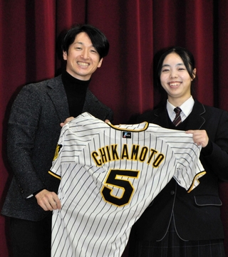 生徒会長の髙見茉央さん（右）にユニホームを手渡す近本光司選手＝社高校