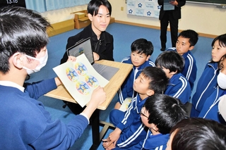 甲南大学生から完成したロゴの説明を受ける九会小学校の児童＝加西市中野町
