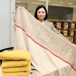 ブランケットを手にする足立織物の足立美由希社長＝多可町中区茂利、同町商工会館