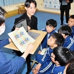 甲南大学生から完成したロゴの説明を受ける九会小学校の児童＝加西市中野町