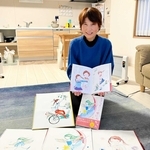 原画を前に絵本を持つ森脇千丹さん＝小野市復井町